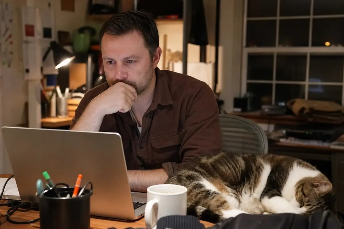 Un homme consulte le détail d'un abonnement pour une caméra connectée depuis son bureau à la maison