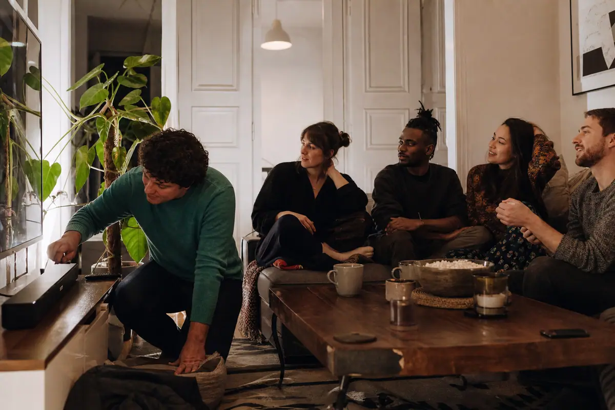 Un groupe d'amis s'installe pour regarder un film devant une barre de son posée sous le téléviseur