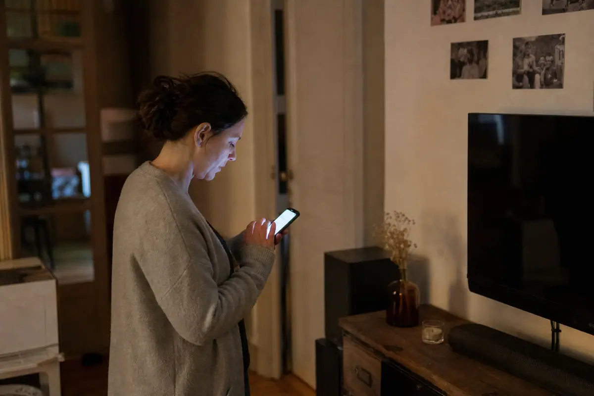 Une femme vérifie la consommation électrique de sa barre de son et de son caisson sur son téléphone