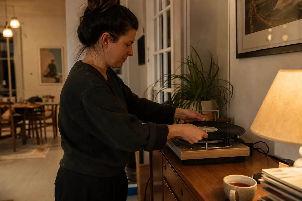 Une femme pose délicatement un disque vinyle sur une platine dans son salon