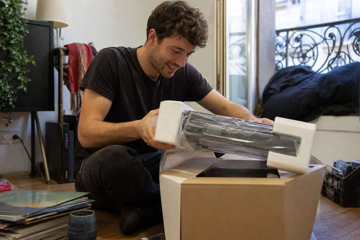 Un jeune homme déballe sa première platine vinyle dans son appartement