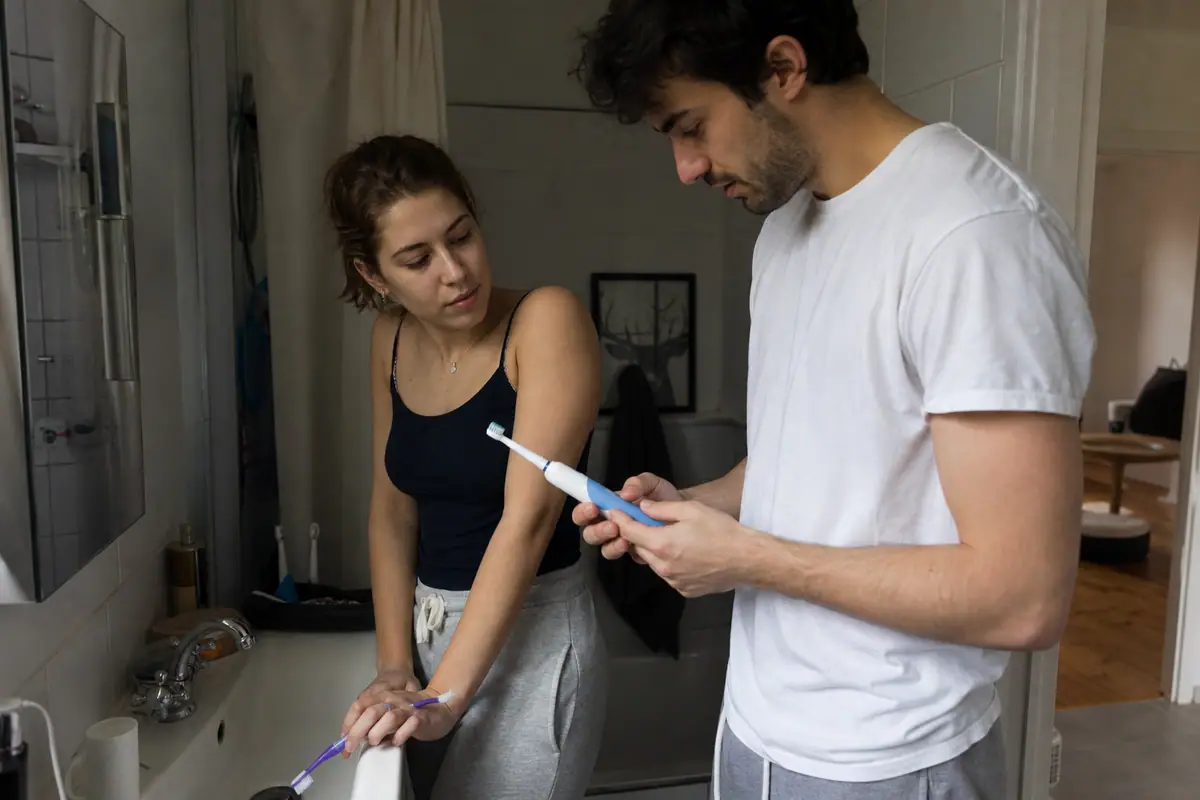 Un couple compare deux brosses à dents électriques dans leur salle de bain