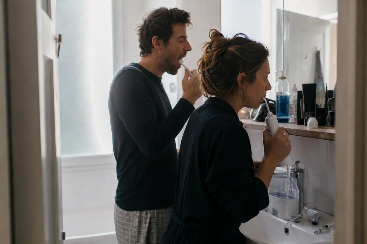 Une femme utilise un hydropulseur devant le miroir de sa salle de bain le matin