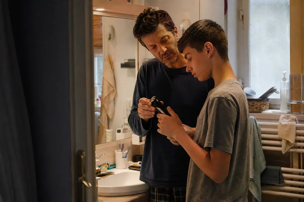 Un père montre à son fils adolescent comment utiliser une tondeuse électrique