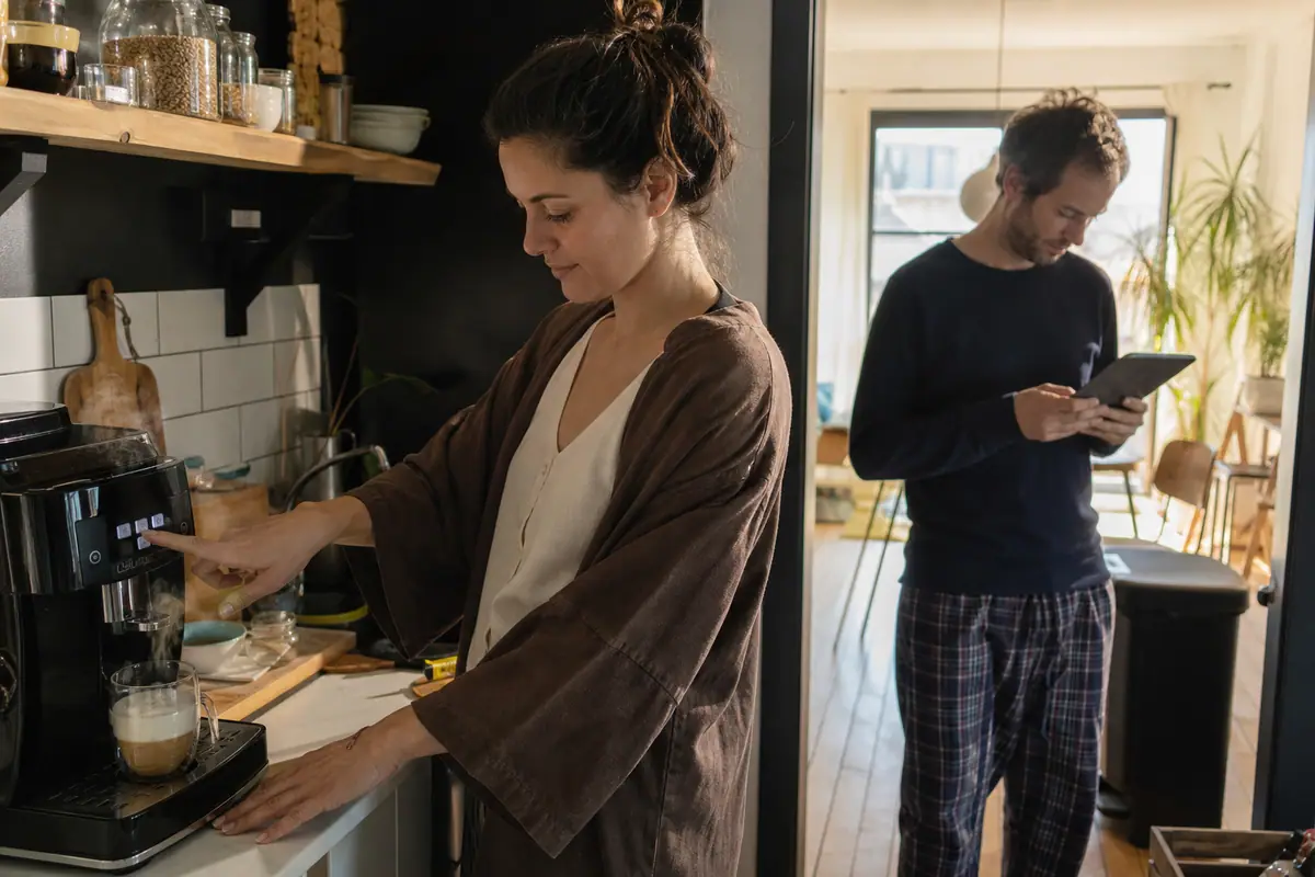 Une femme prépare un café avec une machine à café à grain le matin dans sa cuisine