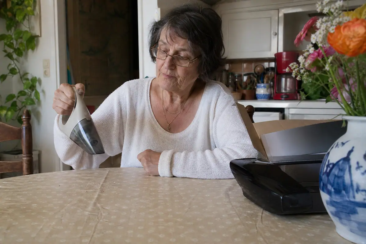 Une femme teste l'autonomie de son ancien aspirateur à main à côté d'un modèle neuf encore dans sa boîte