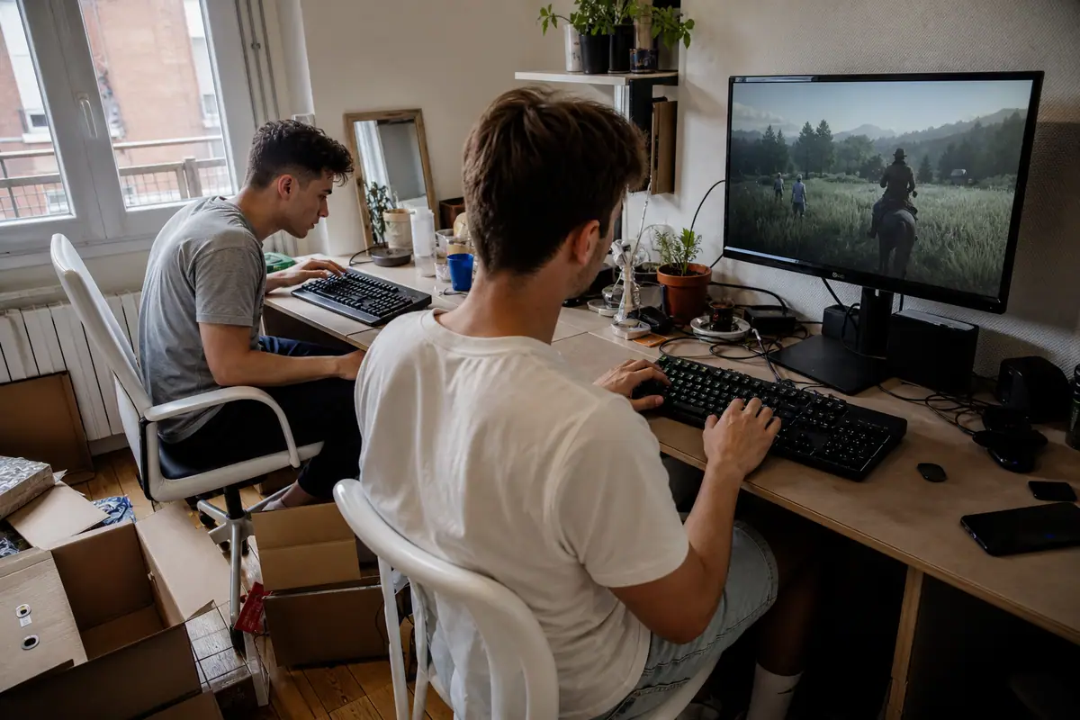 Deux colocataires comparent deux claviers gaming mécaniques posés côte à côte sur un bureau