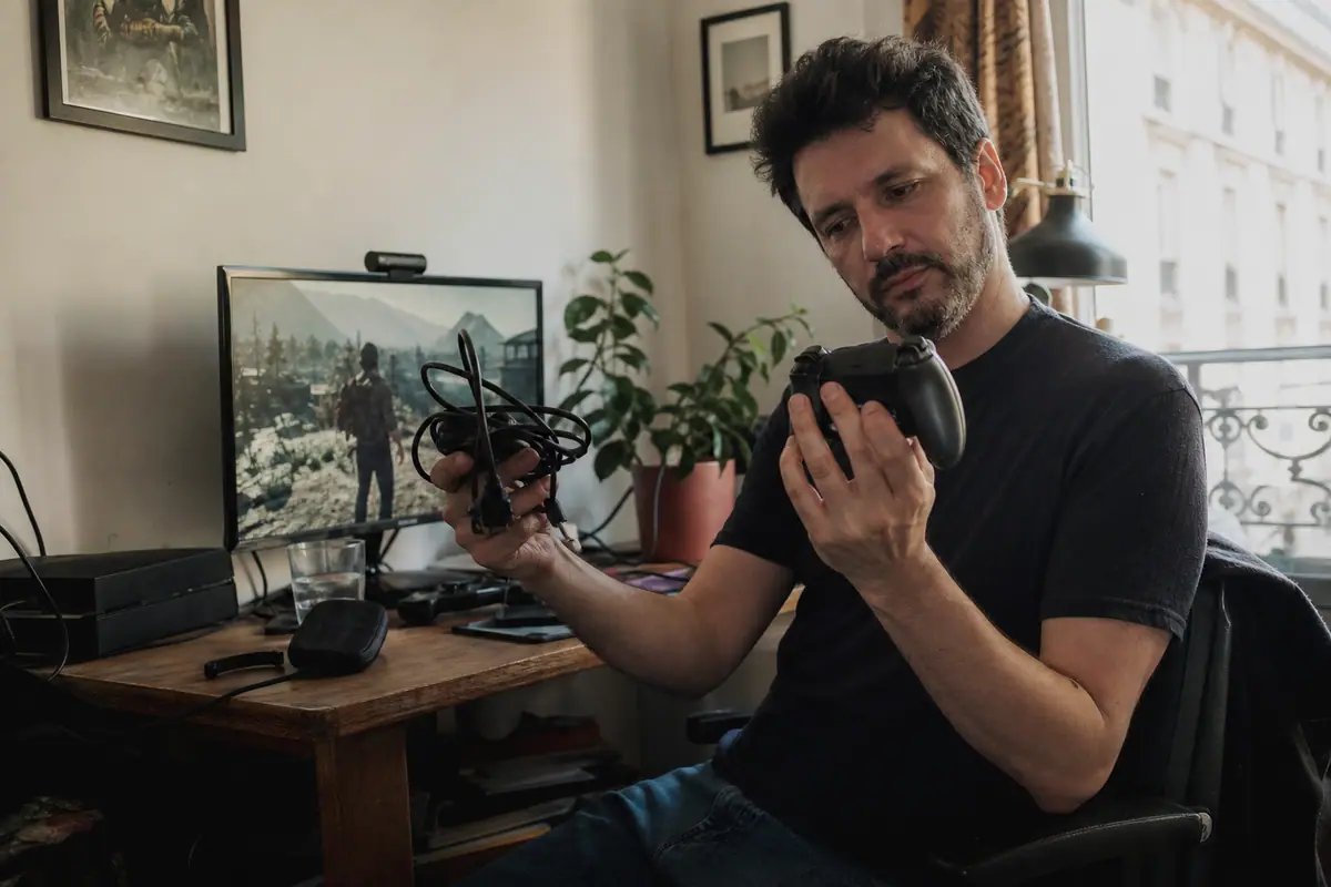 Un homme compare une manette filaire et une manette sans fil posées sur son bureau