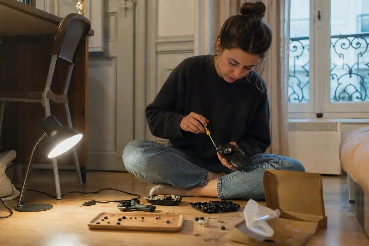 Une jeune femme démonte une ancienne manette usée à côté de la boîte de son nouveau modèle