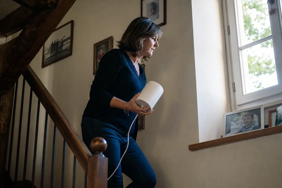 Une femme cherche le meilleur emplacement pour une borne Wifi mesh à l'étage de sa maison