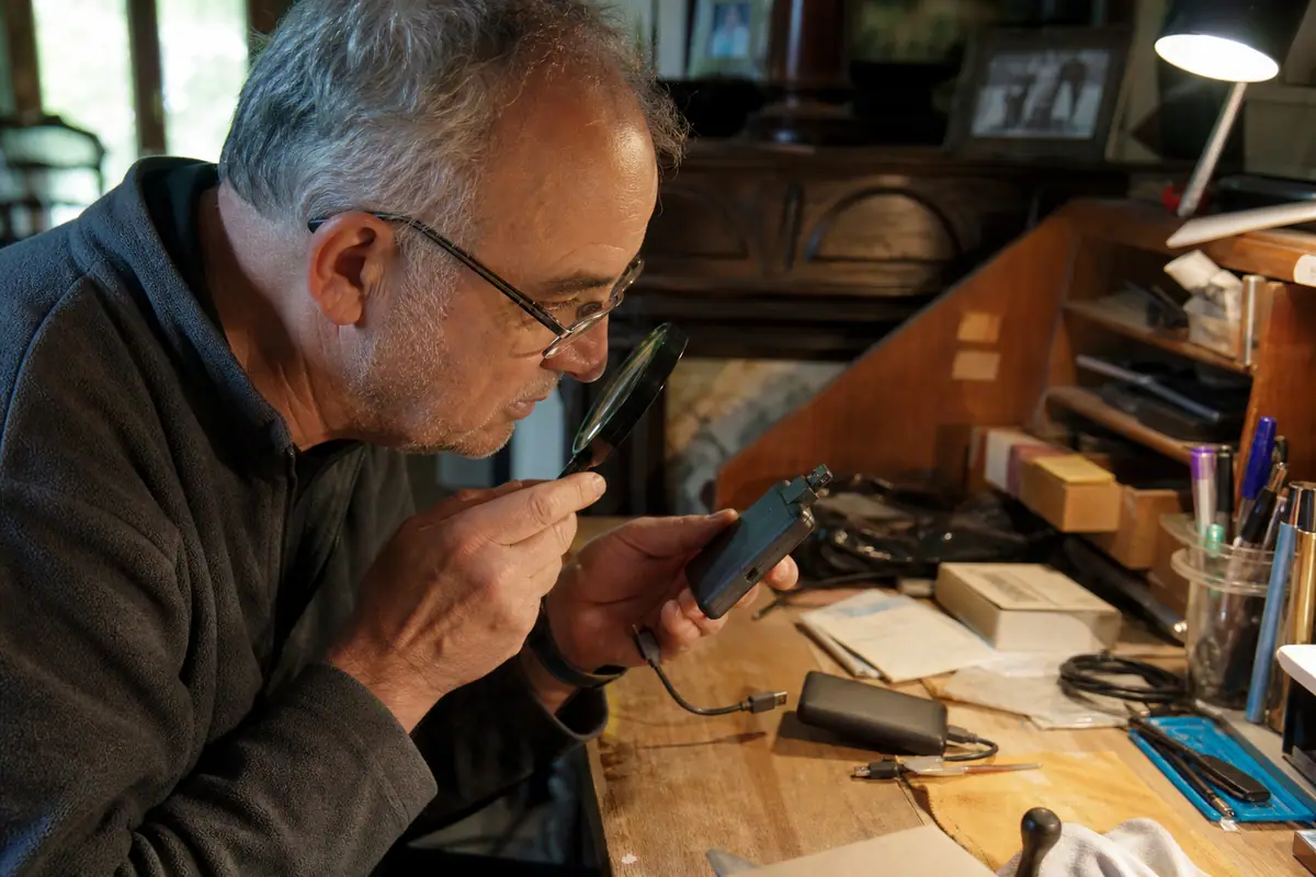 Un homme examine un ancien SSD externe et son câble USB C usé à côté d'un modèle plus récent