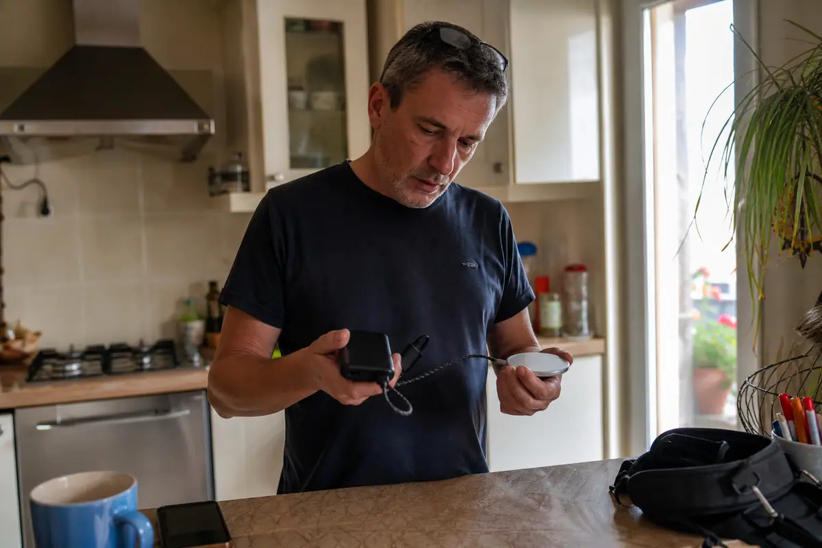 Un homme compare une batterie externe filaire et une batterie magnétique posées sur un plan de travail