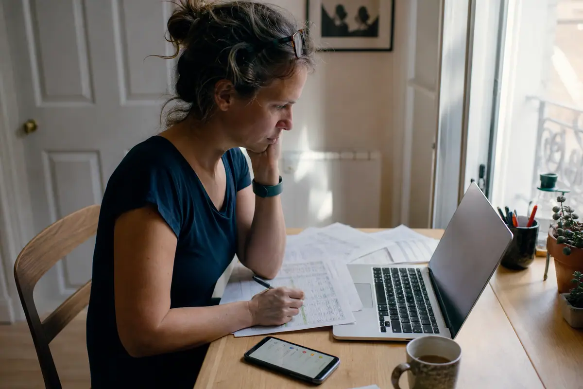 Une femme vérifie ses abonnements sur son relevé bancaire, un bracelet connecté sans écran au poignet