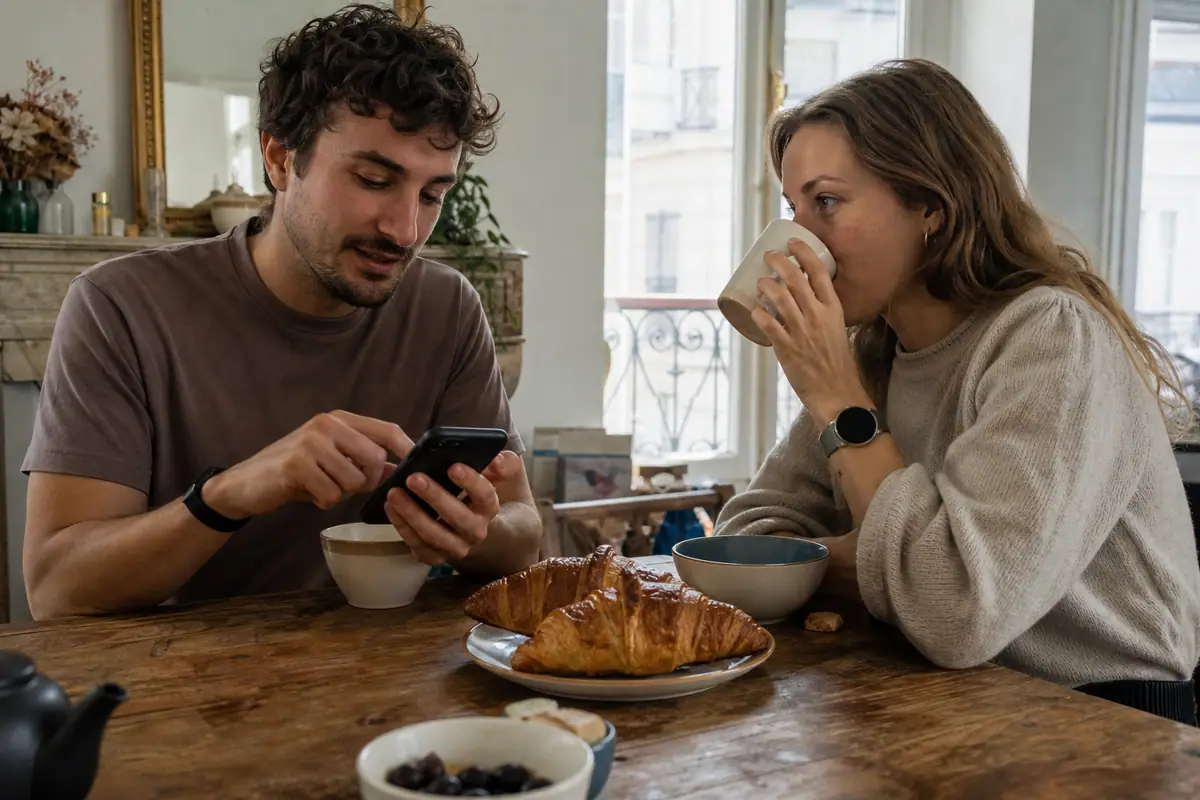 Un jeune couple compare au petit déjeuner les données d'un bracelet d'activité et d'une montre connectée