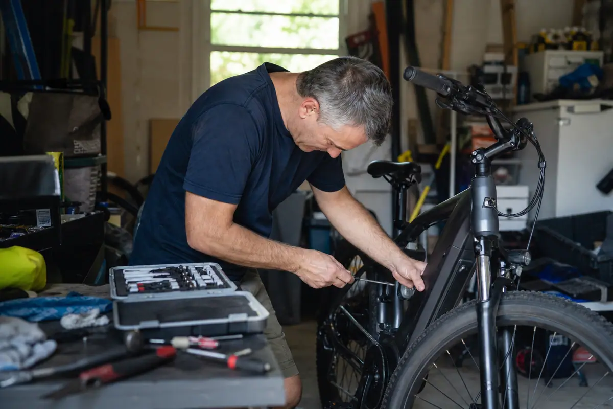 Un homme vérifie les freins et la pression des pneus de son vélo électrique dans son garage