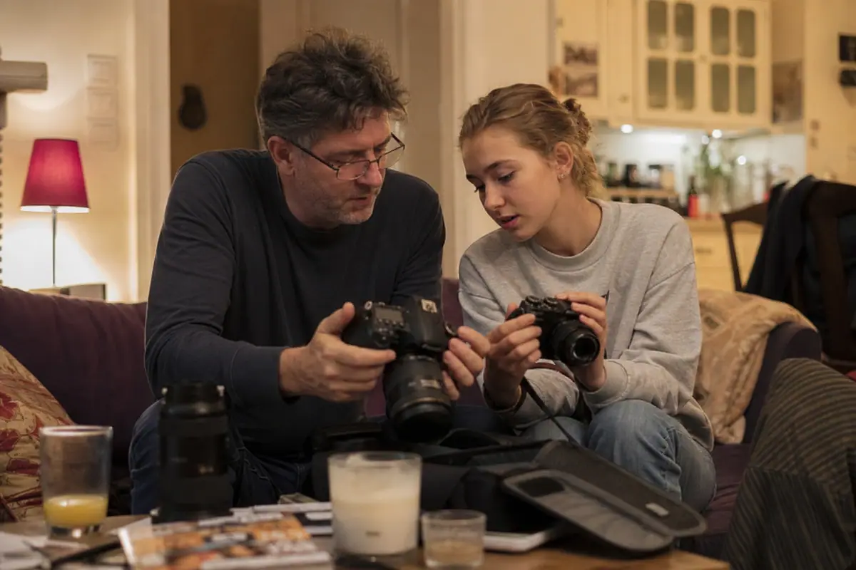 Un père et sa fille comparent un ancien reflex et un appareil photo hybride récent