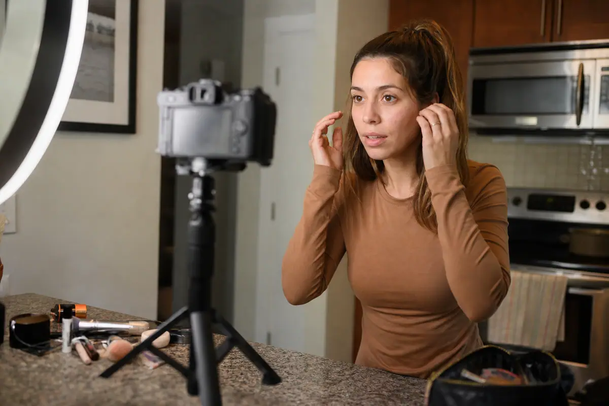 Une créatrice de contenu filme avec un appareil photo hybride monté sur un petit trépied de bureau