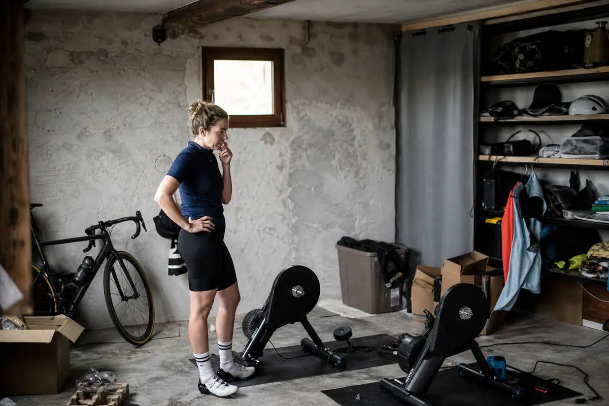 Une femme compare deux home trainers installés côte à côte dans son garage transformé en salle d'entraînement