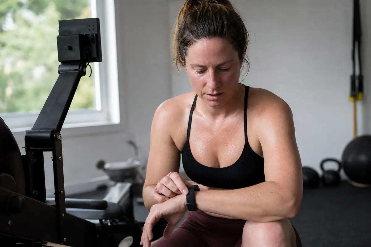 Une femme vérifie les calories brûlées sur sa montre connectée après une séance de rameur