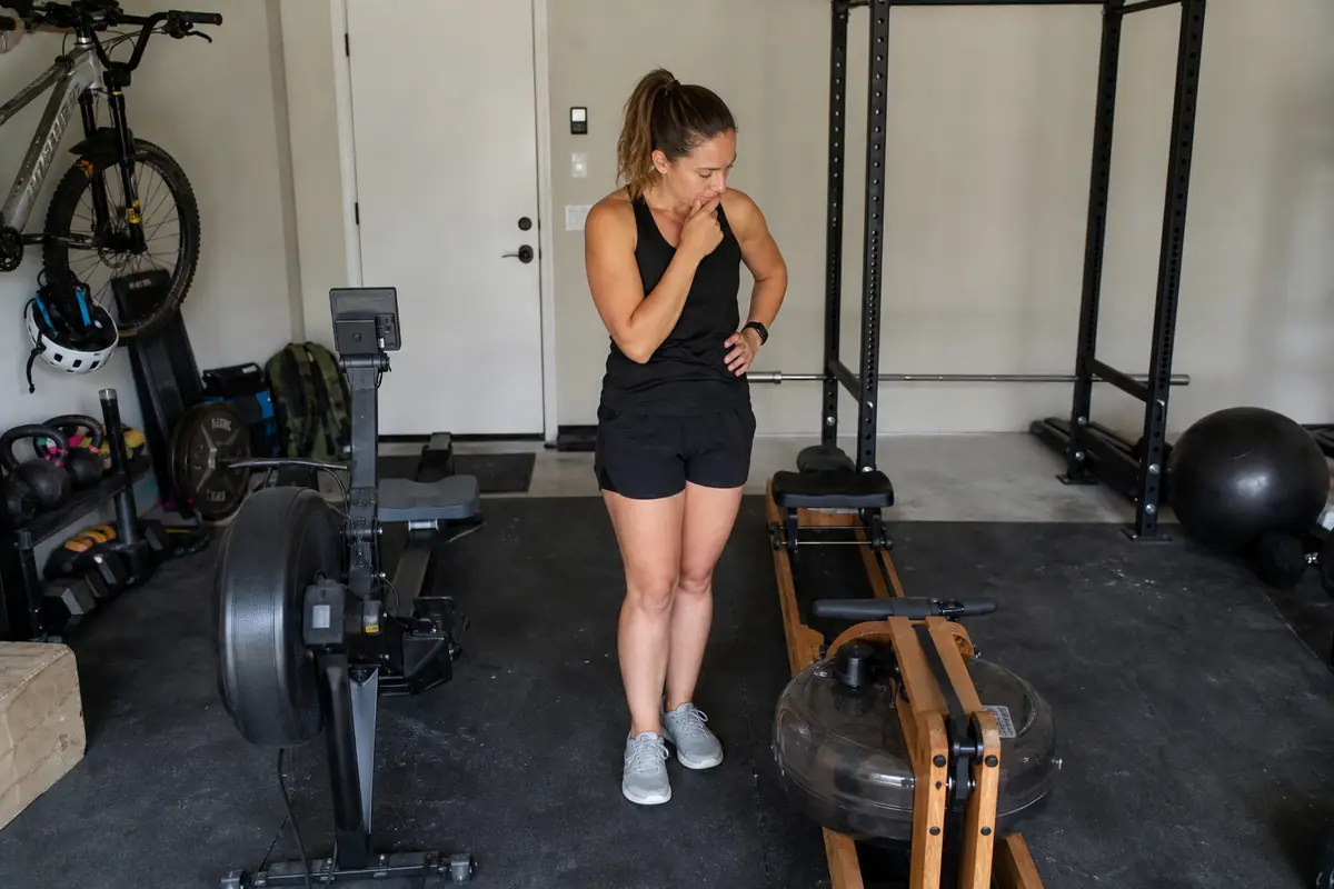 Une femme compare deux rameurs différents installés dans son garage aménagé en salle de sport